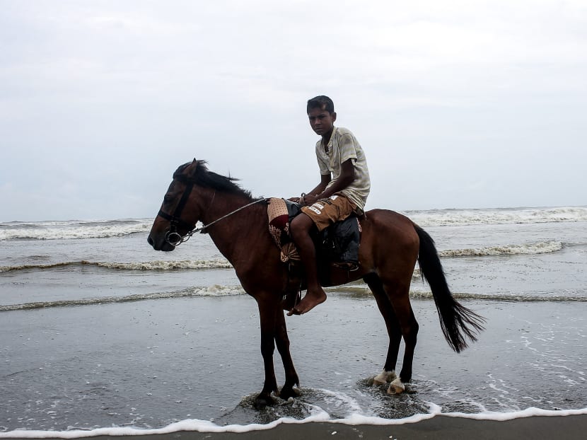 A youth rides a horse while he waits for customers along a beach in Cox's Bazar, Bangladesh on June 16, 2021.