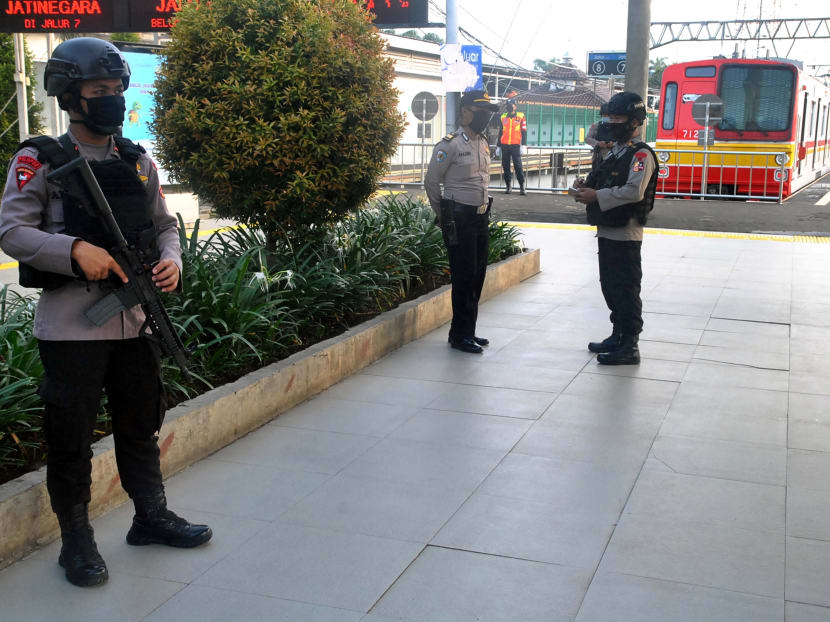 Armed police officers stand guard at a train station in Bogor, near Jakarta, on April 15, 2020.