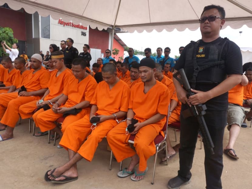 Indonesian police officers guard over convicted drug dealers during a ceremony by the National Anti-Narcotics Agency to destroy seized drugs in Jakarta on Dec 28, 2017.