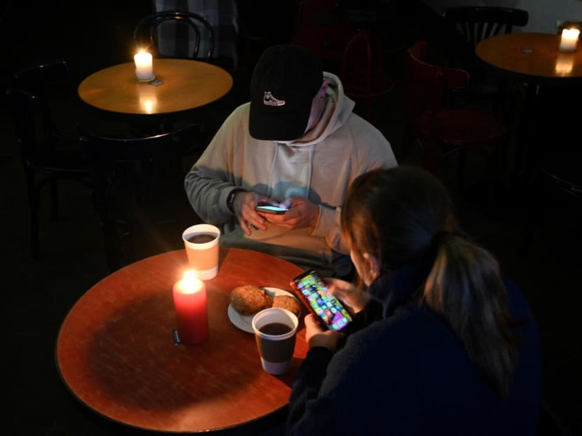 People rest in a coffee shop in Lviv as the city lives through a scheduled power outages on Nov 24, 2022, after the latest Russian massive airstrikes on the Ukrainian energy infrastructure