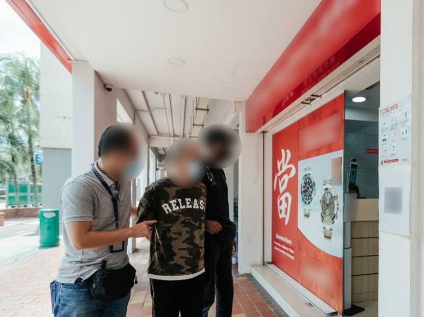 A robbery suspect being led to a pawnshop in Woodlands after his arrest.