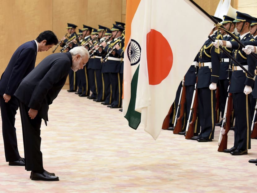 Indian PM Narendra Modi (right) and Japanese PM Shinzo Abe bow to their flags as they review an honour guard in Tokyo yesterday. Mr Modi paid tribute to the ‘growing convergence’ of their views. PHOTO: AFP POOL