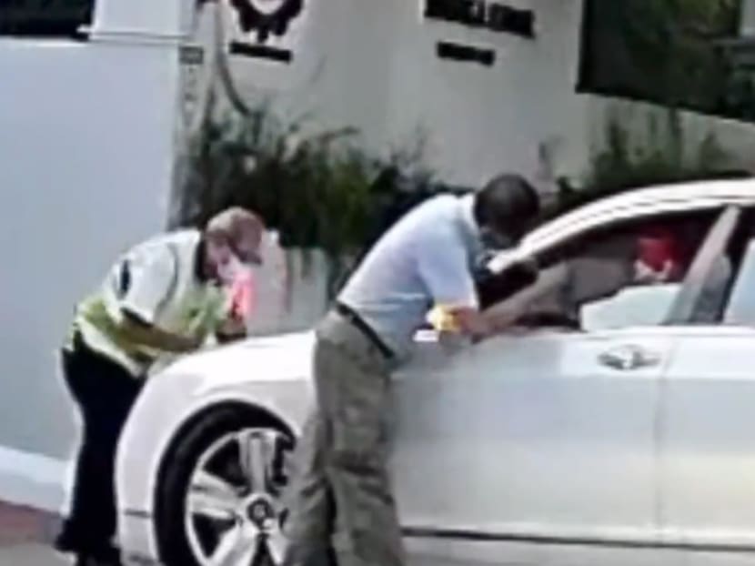 A screenshot from a video showing a security officer and a staff member of Red Swastika School preventing a car from entering the school compound. A screenshot from a video showing a security officer and a staff member of Red Swastika School preventing a car from entering the school compound.