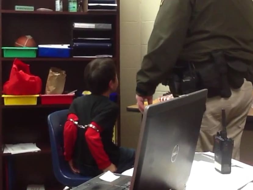 In this image made from video taken in August 2014, and provided by the American Civil Liberties Union on Tuesday, Aug 4, 2015, an 8-year-old boy struggles and cries out as he sits in a chair with handcuffs around his biceps and his arms locked behind him while a school resource officer stands nearby, at an elementary school in Covington, Kentucky. Photo: AP