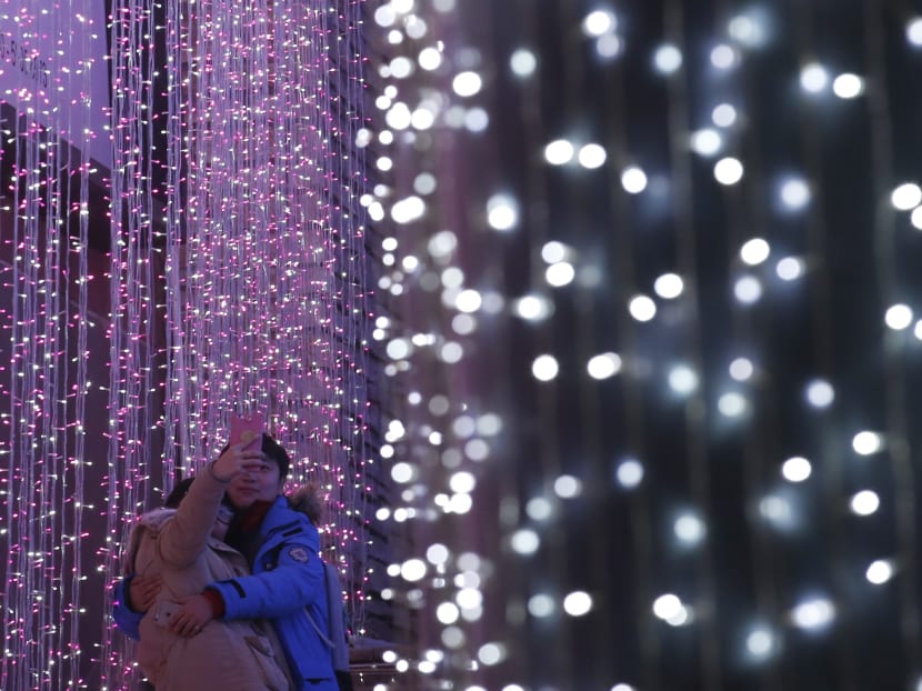 A couple takes a picture in front of a light installation for Christmas celebrations in Beijing. Photo: Reuters