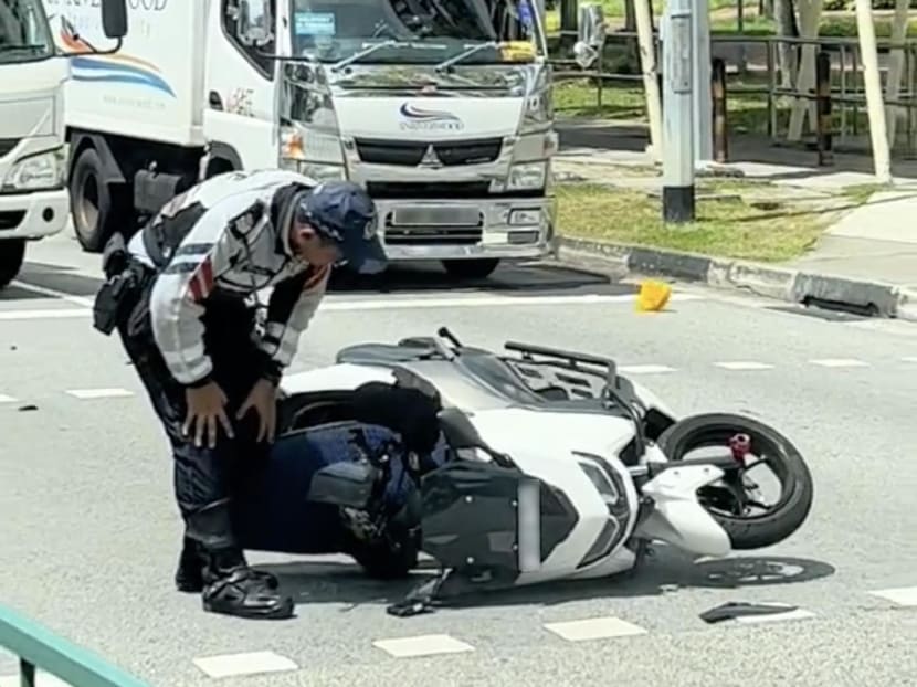 A traffic police officer seen inspecting the motorcycle at the accident scene.