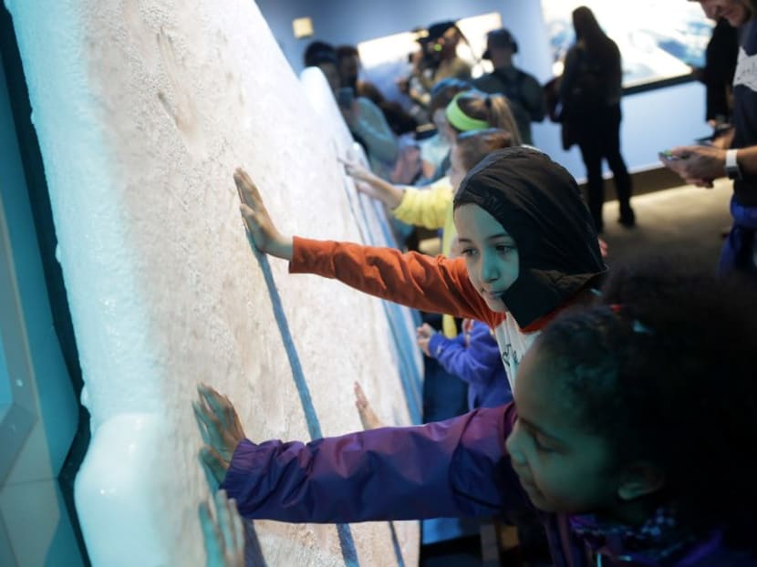 Students on a field trip place their hands on a ice glacier replica during the "Extreme Ice" exhibit at the Museum of Science and Industry in Chicago, Illinois. Photo: AFP