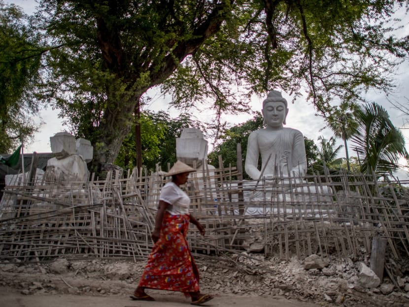 This photo taken on June 21, 2020 shows a woman walking past a marble statue in Sagyin village in Madaya township, about 46km from Mandalay.