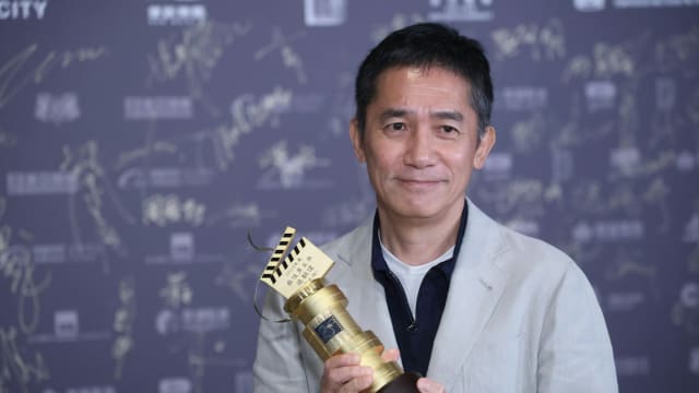 社恐又发作！梁朝伟与男团合照出现“紧张小手”