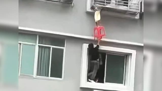 女童头卡七楼窗户缝隙身体悬空 男子爬窗托举凳子救人