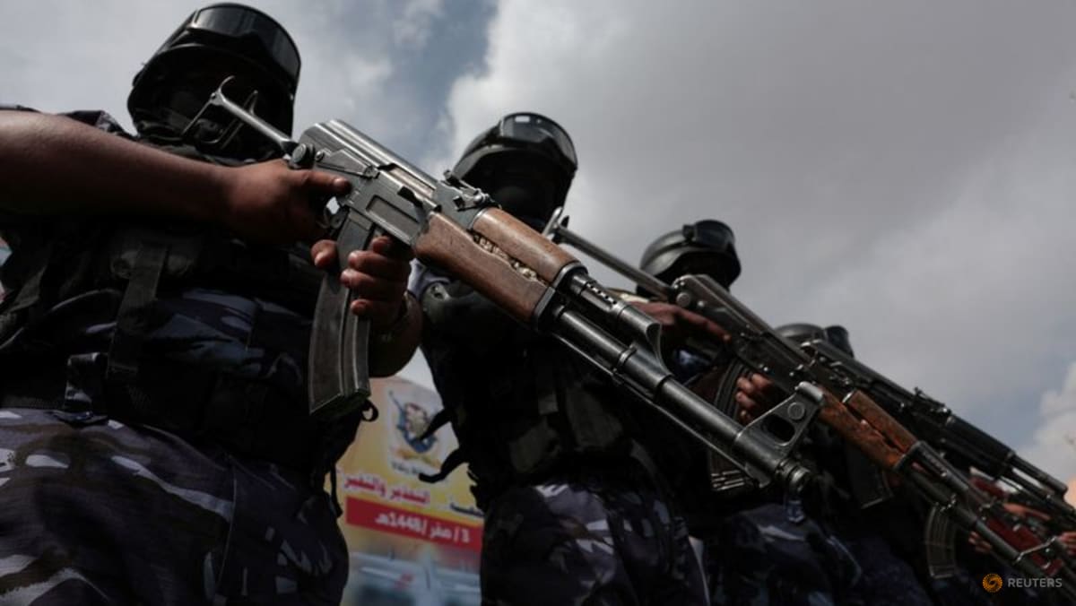 Three armed individuals in tactical gear holding rifles outdoors.