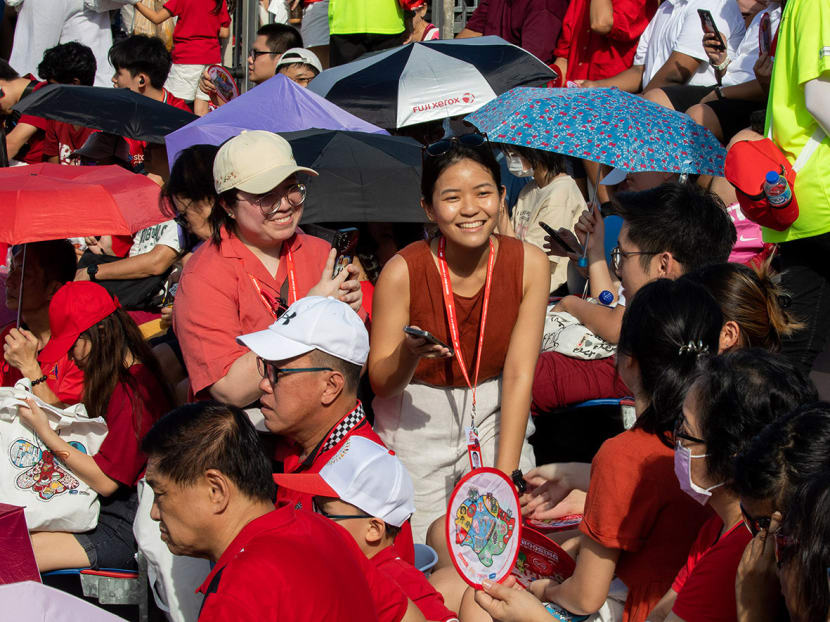 TODAY journalists Jasmine Ong (left, facing camera) and Deborah Lau (right, facing camera) in the stands at the Padang for the 2023 National Day Parade.  