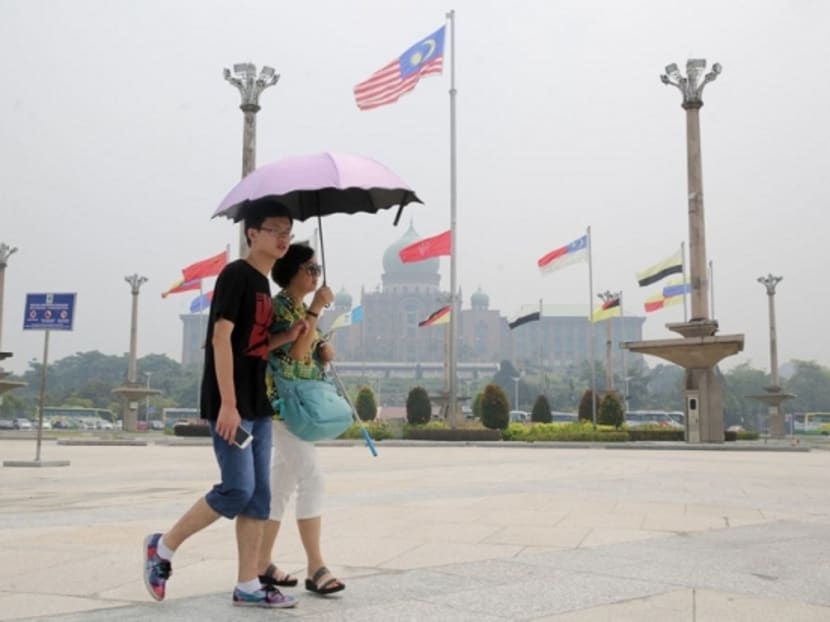 Tourists are seen walking against a hazy backdrop of the Perdana Putra building in Putrajaya on August 16, 2016. Photo: Malay Mail Online