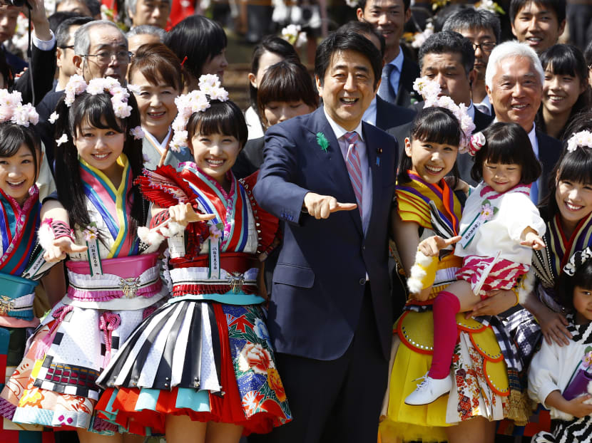 Japan's Prime Minister Shinzo Abe strikes a pose with members of Japan's girl pop unit "Momoiro Clover Z" during the annual cherry blossoms viewing party hosted by Abe at Shinjuku Gyoen National Garden park in Tokyo Saturday, April 18, 2015. Photo: AP