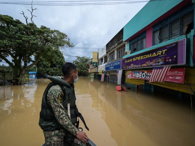 A member of the Malaysian Army looks on as he rides a boat past flooded shops following heavy monsoon downpour in Kampung Desa Bakti in Malaysia's Pahang State on Thursday, Jan 7, 2021.