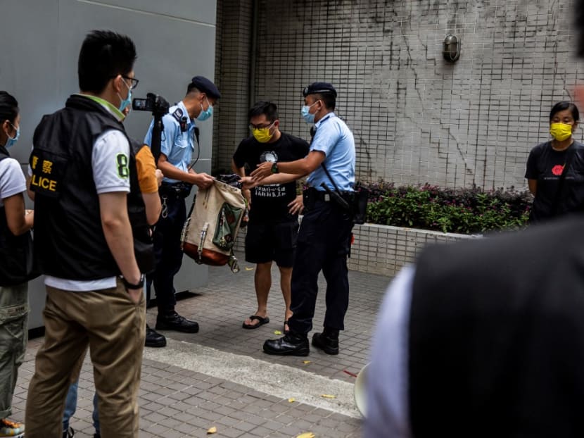 Police search the bag of pro-democracy activist Raphael Wong (C), from the League of Social Democrats, during a protest in Hong Kong on July 1, 2021, while a flag-raising ceremony to mark the 24th anniversary of Hong Kong's handover from Britain is held near by. Police search the bag of pro-democracy activist Raphael Wong (C), from the League of Social Democrats, during a protest in Hong Kong on July 1, 2021, while a flag-raising ceremony to mark the 24th anniversary of Hong Kong's handover from Britain is held near by.