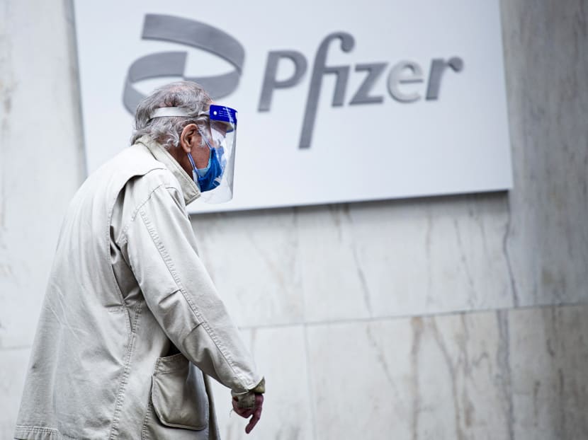 A man wearing facemask and shield walks past the Pfizer headquarters in New York, US on March 11, 2021.