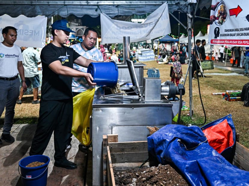 This picture taken on April 3, 2024 shows a Ramadan bazaar trader throwing food waste into a composting machine in Kuantan, Malaysia's Pahang state. 