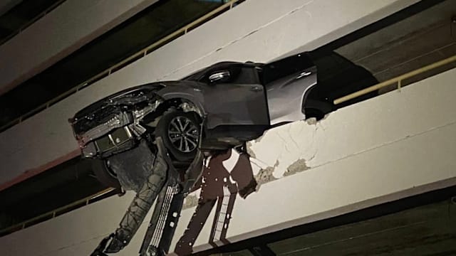 司机误踩油门 泰国轿车撞破围墙险坠楼