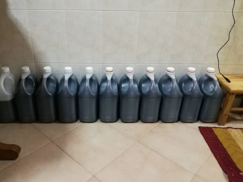 Stocks of the illegal cough syrup in large containers seized from a HDB flat.