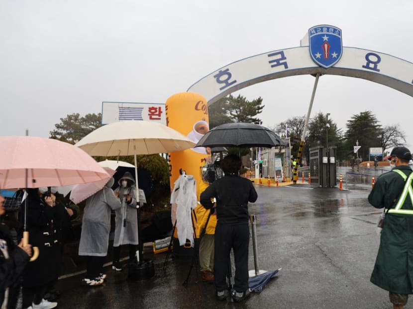 A South Korean soldier (right) stands as reporters and BTS fans gather in front of the main gate of a military boot camp in Nonsan on Dec 11, 2023.