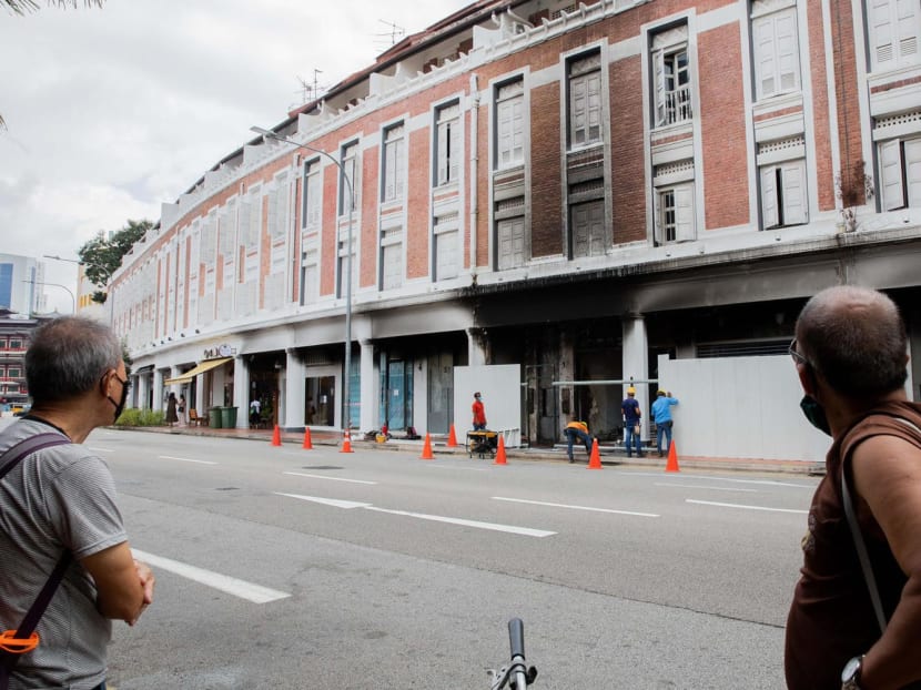 Passers-by watching as workers cordoned off the site where a BMW driven by Jonathan Long Junwei, 29, crashed into a stretch of shophouses along Tanjong Pagar Road in the early morning of Feb 13, 2021.