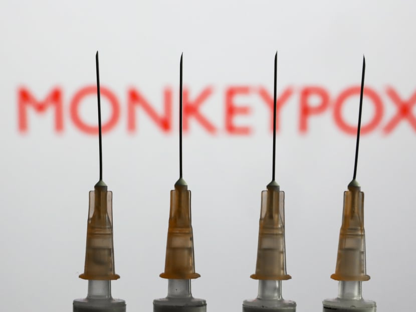 Medical syringes are seen with "Monkeypox" sign displayed on a screen in the backgound in this illustration photo.
