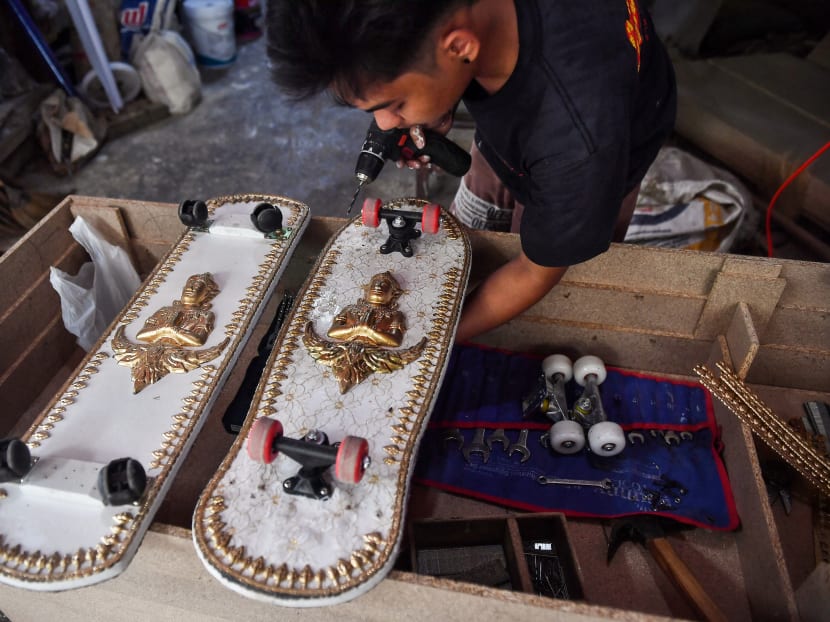 An employee from the Burapha coffin shop puts wheels on skateboards, made from wood used for coffins, in Bangkok, Thailand on March 19, 2021