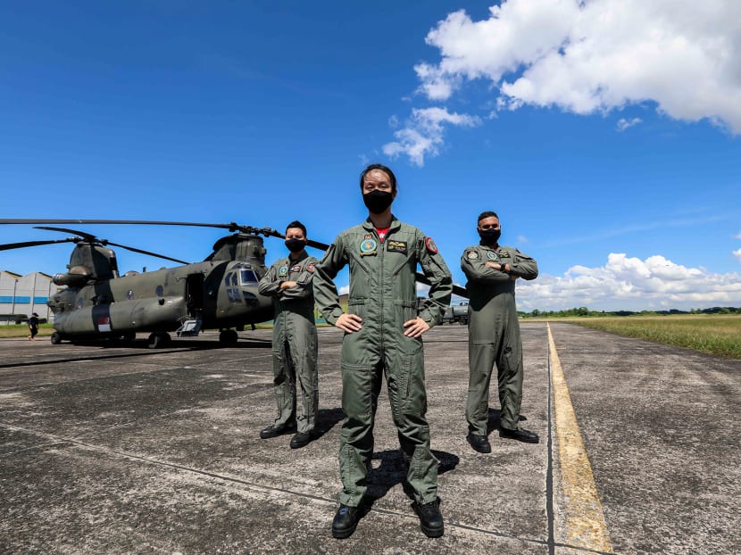 (Left to right ) Captain Eugene Chua Wenjun, Captain Trixie Tang Yingsi and Military Expert 2 Sukhdesh Singh Sandhu, part of the Republic of Singapore Air Force team participating in the NDP 2020 state flag flypast, posing for a picture with the CH-47 Chinook helicopter at Sembawang Air Base on July 16, 2020.