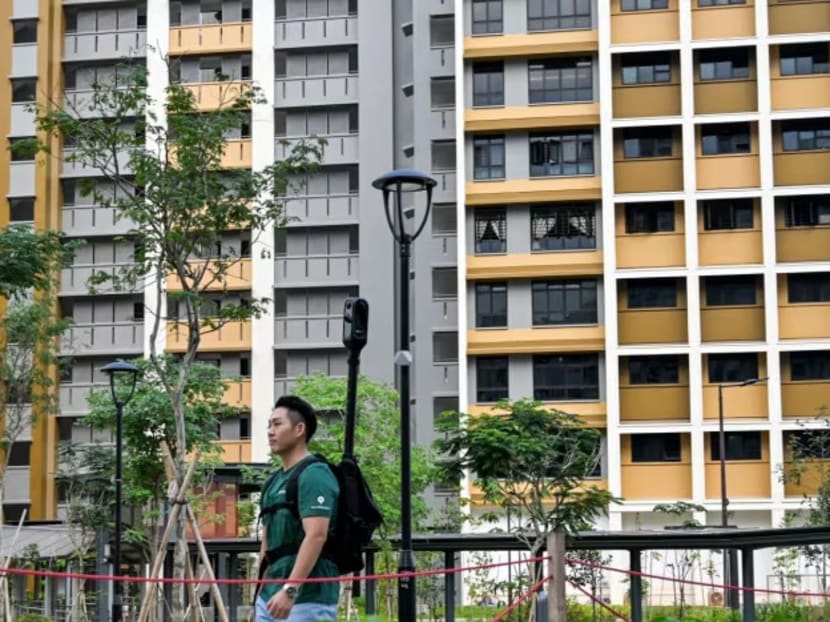 A GrabMap employee walks past blocks of HDB flats in Tengah while wearing a camera backpack used to map walking paths.