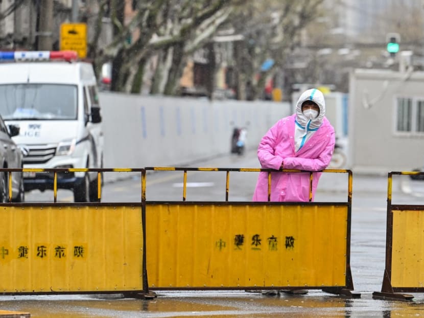 A worker wearing protective gear stands next to barriers placed to close off streets around a locked down neighbourhood after the detection of new cases of Covid-19 in the Huangpu district of Shanghai on March 21, 2022. A worker wearing protective gear stands next to barriers placed to close off streets around a locked down neighbourhood after the detection of new cases of Covid-19 in the Huangpu district of Shanghai on March 21, 2022.