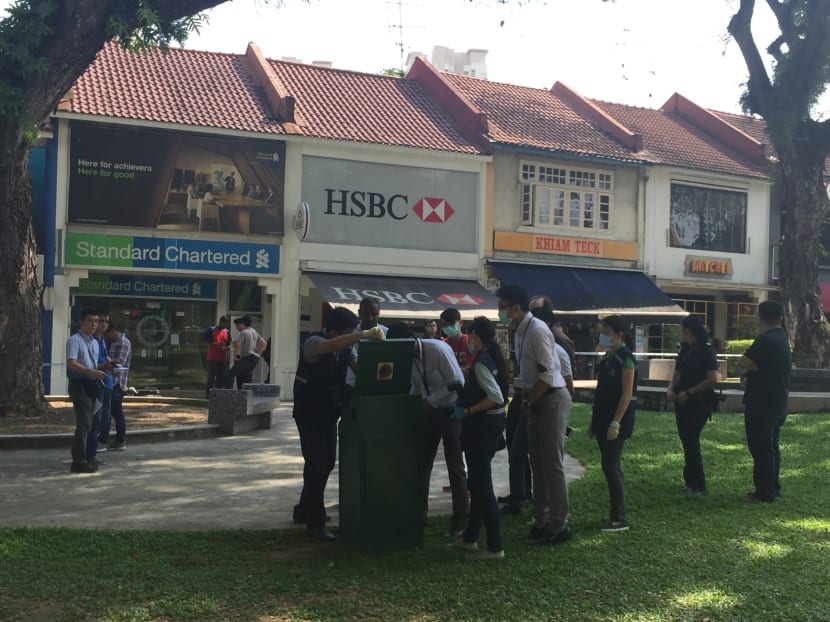 Police investigating the contents of a dustbin within the cordoned-off area outside the Standard Chartered bank in Holland Village that was robbed on Thursday. Photo: Laura Philomin/TODAY