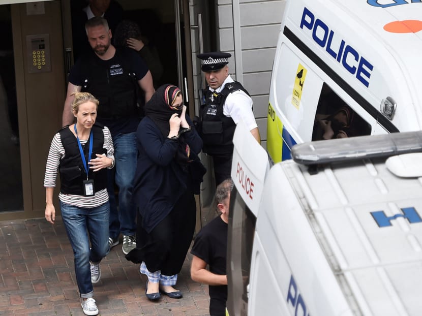 Police officers escorting a woman to a police van after raiding a block of flats in Barking, east London, on Sunday. There are concerns over whether Mrs May’s proposed laws could be effective while protecting civil liberties.  Photo: Reuters