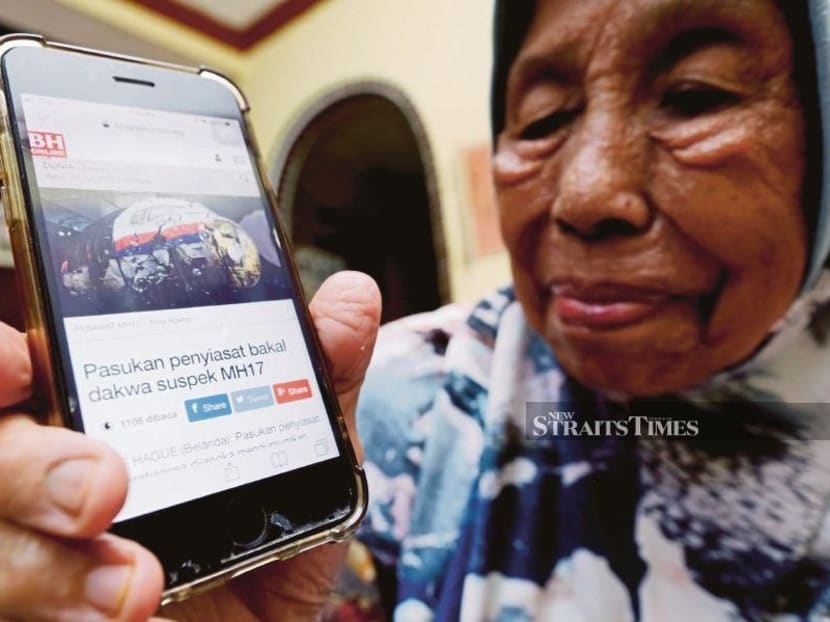 Mdm Maimoun Sarpan, whose son was a crew member of Malaysia Airlines Flight MH17, showing an online article on the naming of the suspects in the downing of the aircraft, on Wednesday.