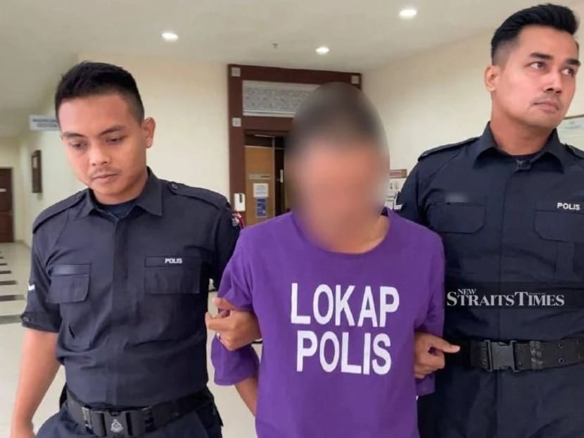 The man (centre) escorted by police in court ahead of the trial in Muar.