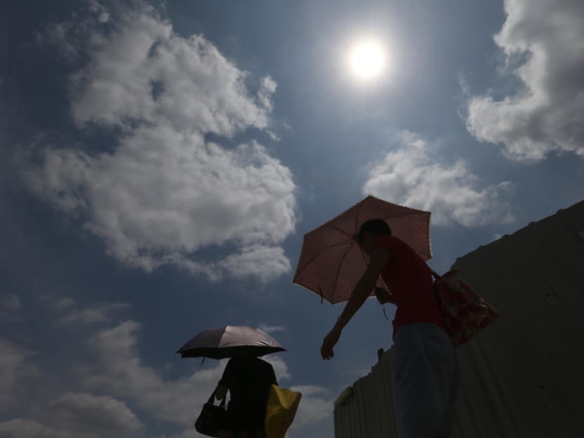 Pedestrians holding up umbrellas for shelter from the hot sun in Singapore. Pedestrians holding up umbrellas for shelter from the hot sun in Singapore.