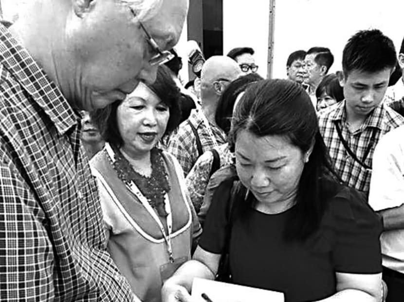 (From left): Emeritus Senior Minister Goh Chok Tong signing a copy of Once Upon A Tai Seng Village for a reader as co-author Ann Phua looks on. At the book launch, Mr Goh recalled how an episode in Tai Seng and Defu Industrial Estate led the Government to change policies to be more flexible. Photo: Facebook/Once Upon Tai Seng