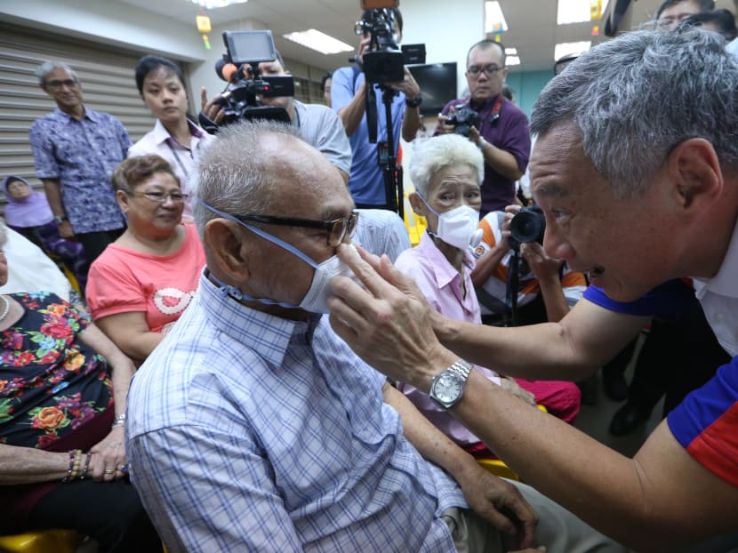 Prime Minister Lee Hsien Loong helps Teck Ghee resident Mr Mohamed Ali bin Jofrie, 84, put on a AIR+Smart Mask and guided him on the correct way to use the Micro Ventilator at COMNET@Teck Ghee (Senior Activity Centre). Photo: Ooi Boon Keong/TODAY