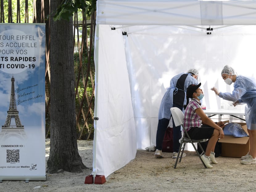 A health worker administers a Covid-19 antigenic test to a visitor, as a banner reads 'The Eiffel Tower welcomes you for your anti Covid-19 quick tests', near The Eiffel Tower in Paris, France on July 21, 2021.