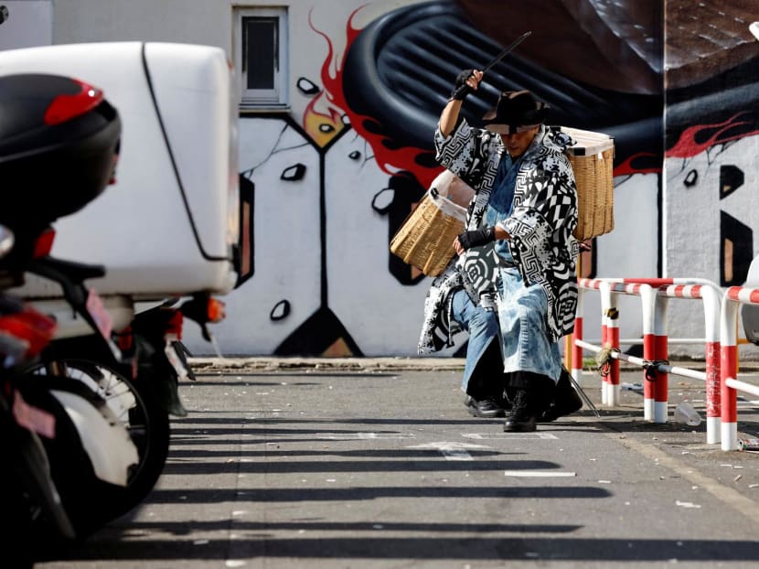 Keisuke Naka, member of Gomihiroi Samurai (trash-picking samurai) clad in denim yukata, picks up trash at a parking lot of Ikebukuro in the morning after Halloween while performing samurai sword fighting by using his fire scissors in Tokyo, Japan on Nov 1, 2023. 