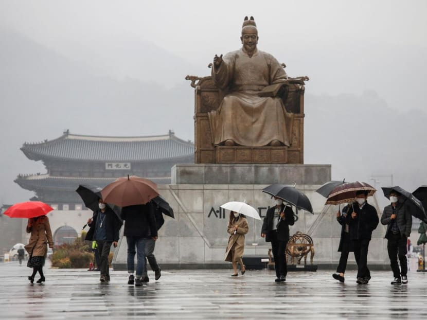 Pedestrians wearing masks walk with umbrellas as it rains amid the Covid-19 pandemic in central Seoul, South Korea on Nov 19, 2020. 