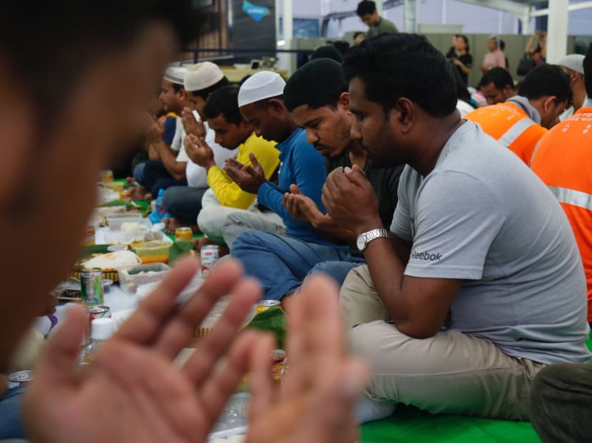 Muslim migrant workers breaking fast at dusk at a communal iftar dinner at the Paya Lebar Quarter during the holy month of Ramadan. Photo: Najeer Yusof/TODAY