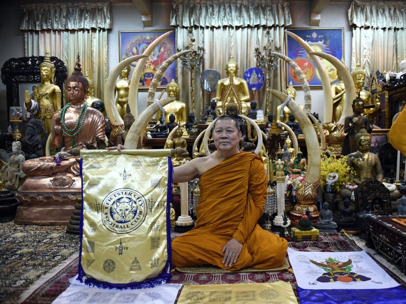 Thai Buddhist monk Phra Prommangkalachan holding a banner emblazoned with sacred patterns surrounding Leicester City Football Club's crest at the Traimitr Withayaram Woraviharn Temple in Bangkok. Phra Prommangkalachan says he and his colleagues have visited the Thai-owned club in England regularly, blessing the pitch and handing out lucky talismans to the players. Photo: AFP