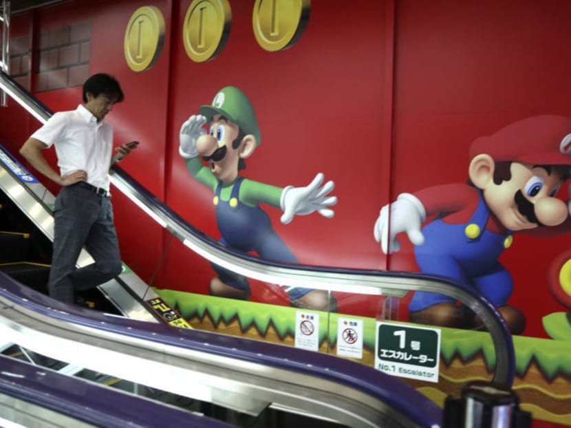 A shopper walks in front of the logo of Nintendo's Super Mario characters at an electronics store in Tokyo, Monday, July 13, 2015. Photo: AP