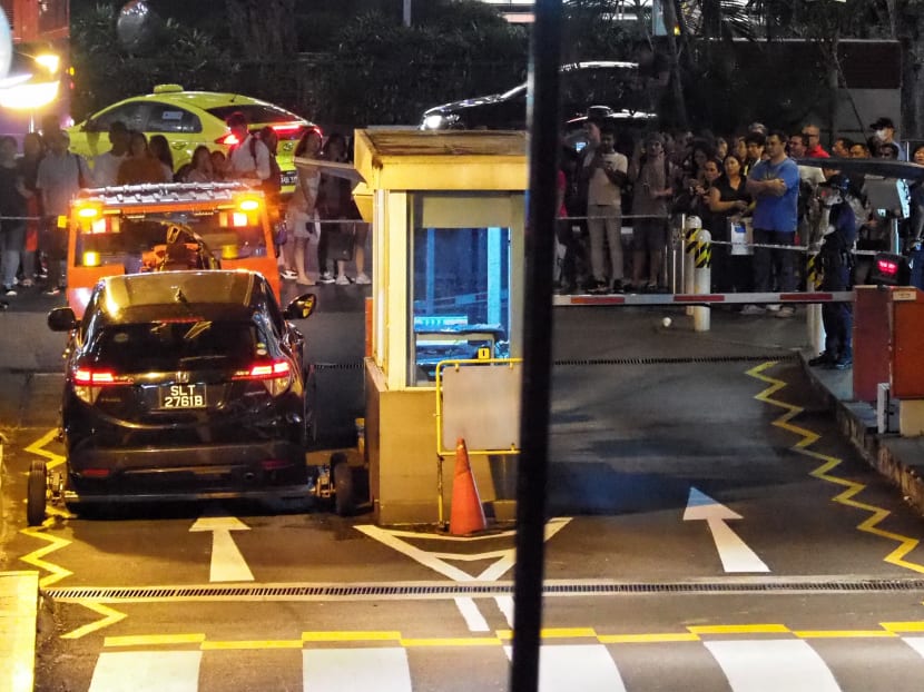 A crowd watching the car involved in Sunday's fatal accident at Lucky Plaza being towed away. Two female pedestrians were killed and four others were injured.