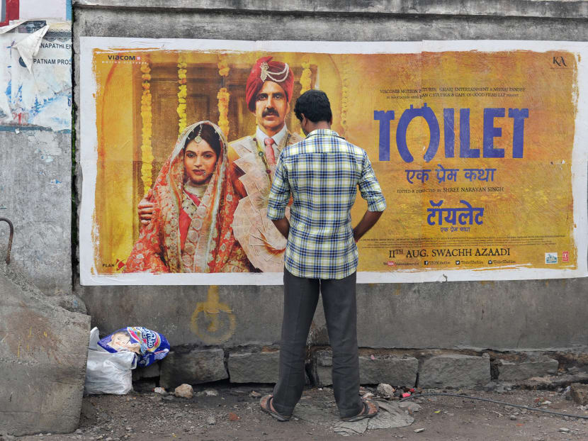 An man urinates on a wall on the roadside in front of a poster for the Hindi film Toilet in Hyderabad on August 12, 2017. Photo: AFP