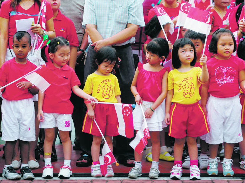 Children of different races waving Singapore flag at a National Day celebration event. TODAY file photo