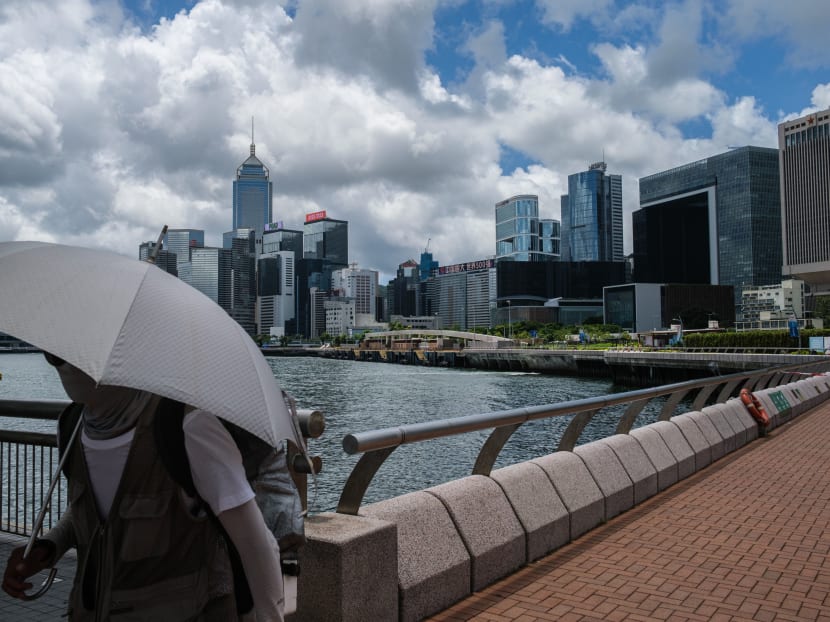 A man walks with his child past a view of commercial buildings and the government headquarters in Hong Kong on Thursday, July 16, 2020. Beijing's tough new security law and US President Donald Trump's order to rescind special trading privileges have blunted Hong Kong's competitive edge and risk turning the finance hub into just another Chinese city, analysts warn.