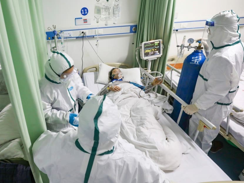 Medical workers in protective suits attend to a coronavirus patient at a designated hospital in Wuhan.