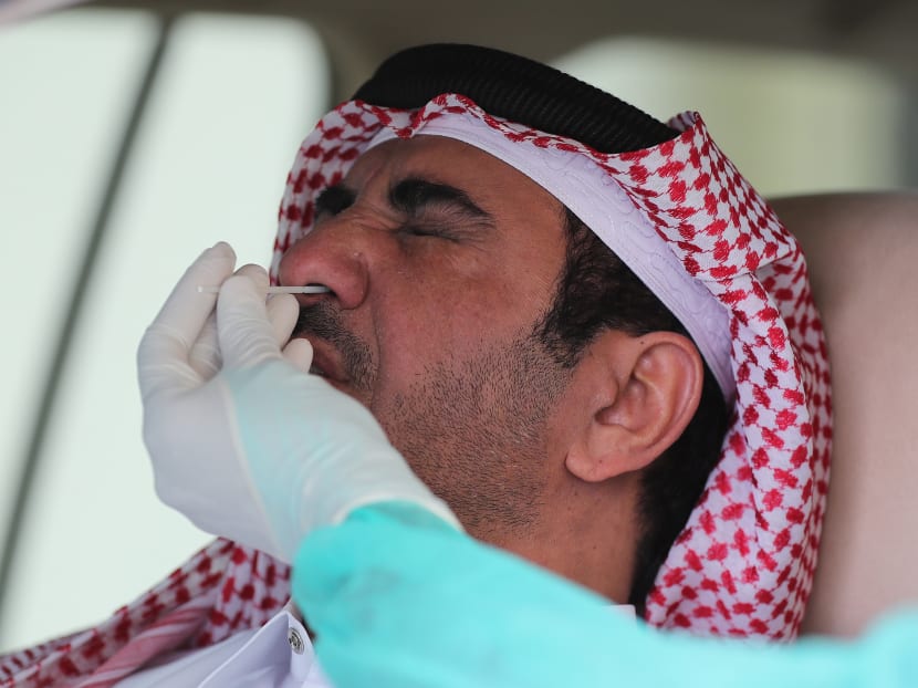 A health worker collects a swab sample from a man at a drive-through Covid-19 testing service in Doha, Qatar, on May 7, 2020.